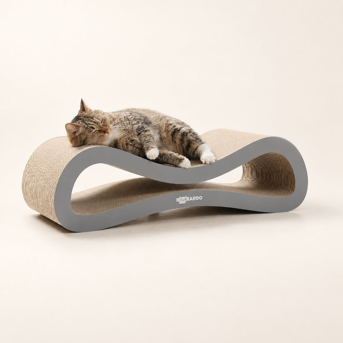 Tabby cat curled up asleep on the Nookaroo Agatha infinity scratcher and lounge on a warm cream background