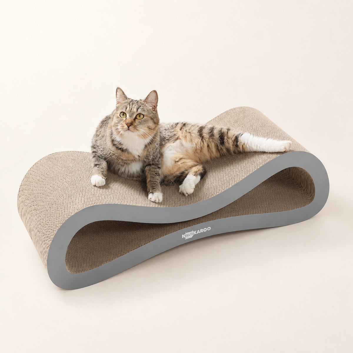 Tabby cat relaxing across the Nookaroo Agatha infinity scratcher and lounge on a warm cream background
