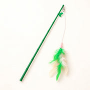 View image 1: Green feather wand with white string and green-and-cream feathers on a warm ivory background