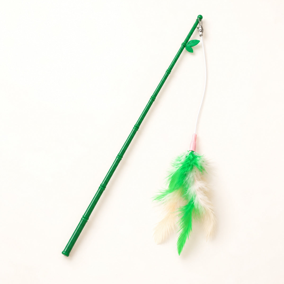 Green feather wand with white string and green-and-cream feathers on a warm ivory background