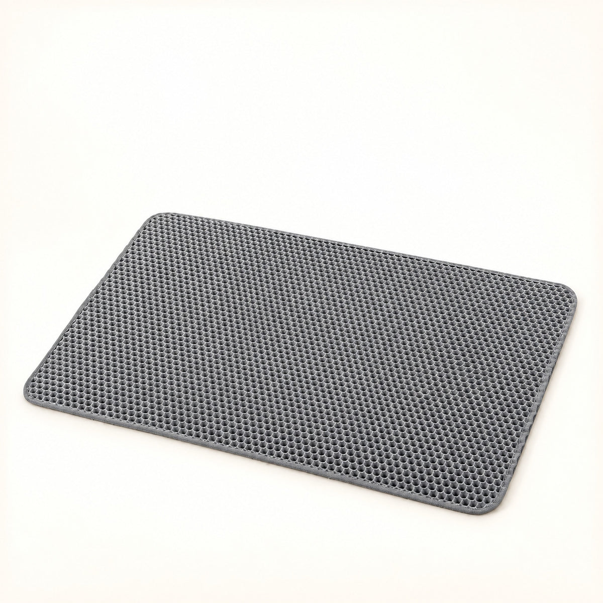 Gray double-layer honeycomb litter mat with rounded corners on a warm ivory background